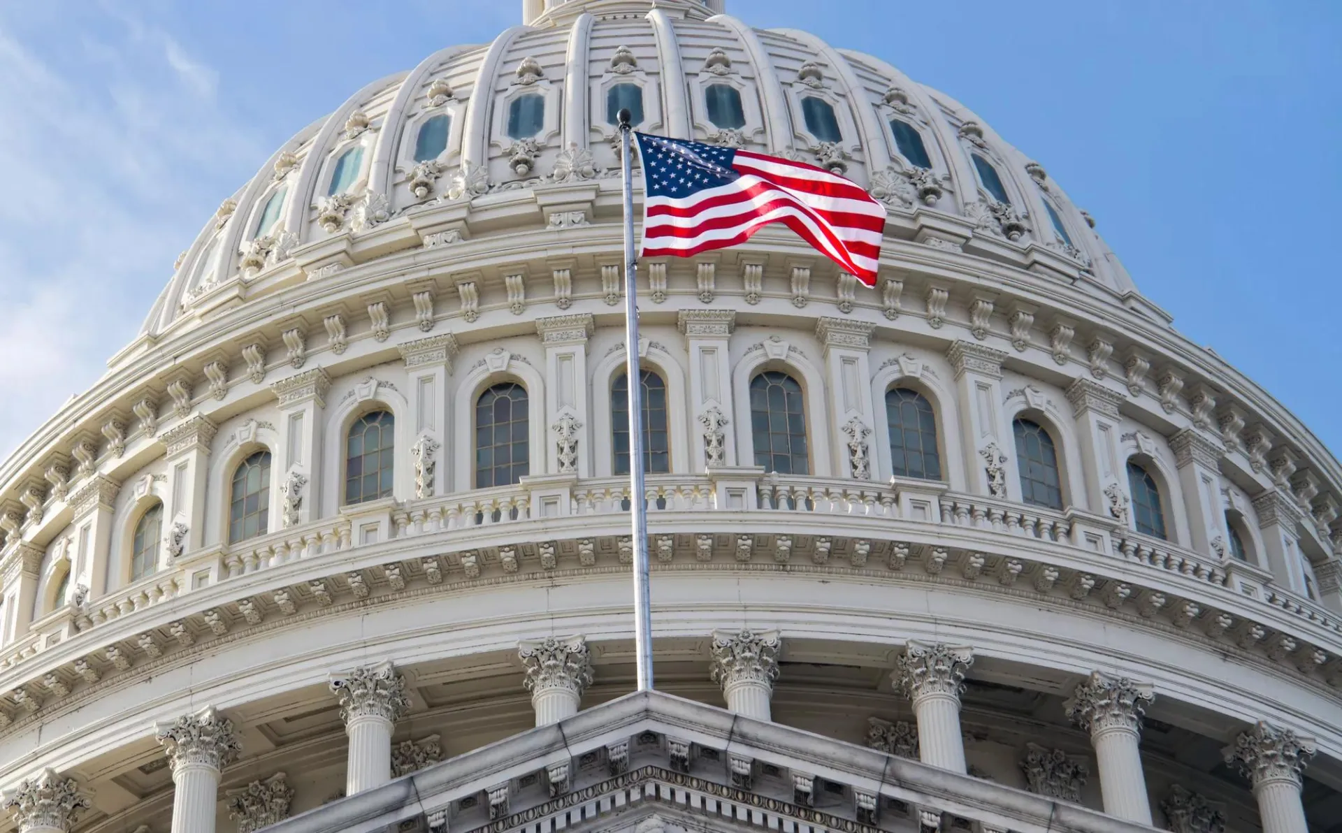 The U.S. flag flying in front of the U.S. Capitol.