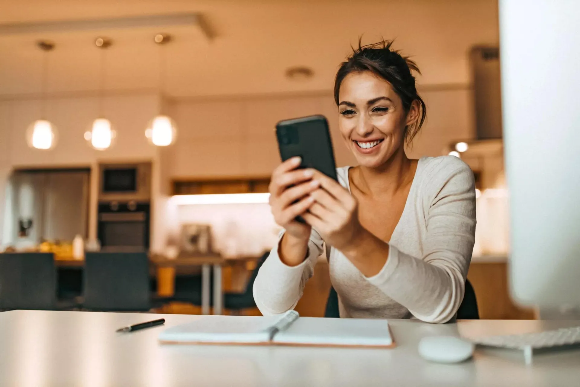 Women sitting at her desk checking her phone.