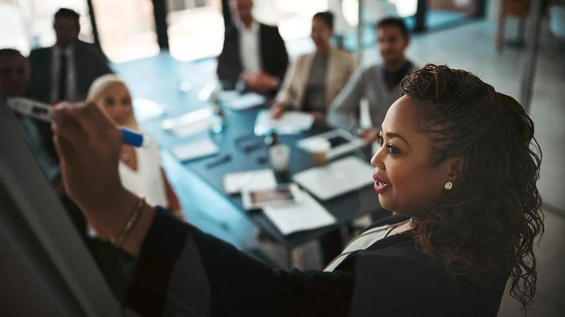 High angle shot of a young businesswoman explaining work related stuff during a presentation to work colleagues in a boardroom.