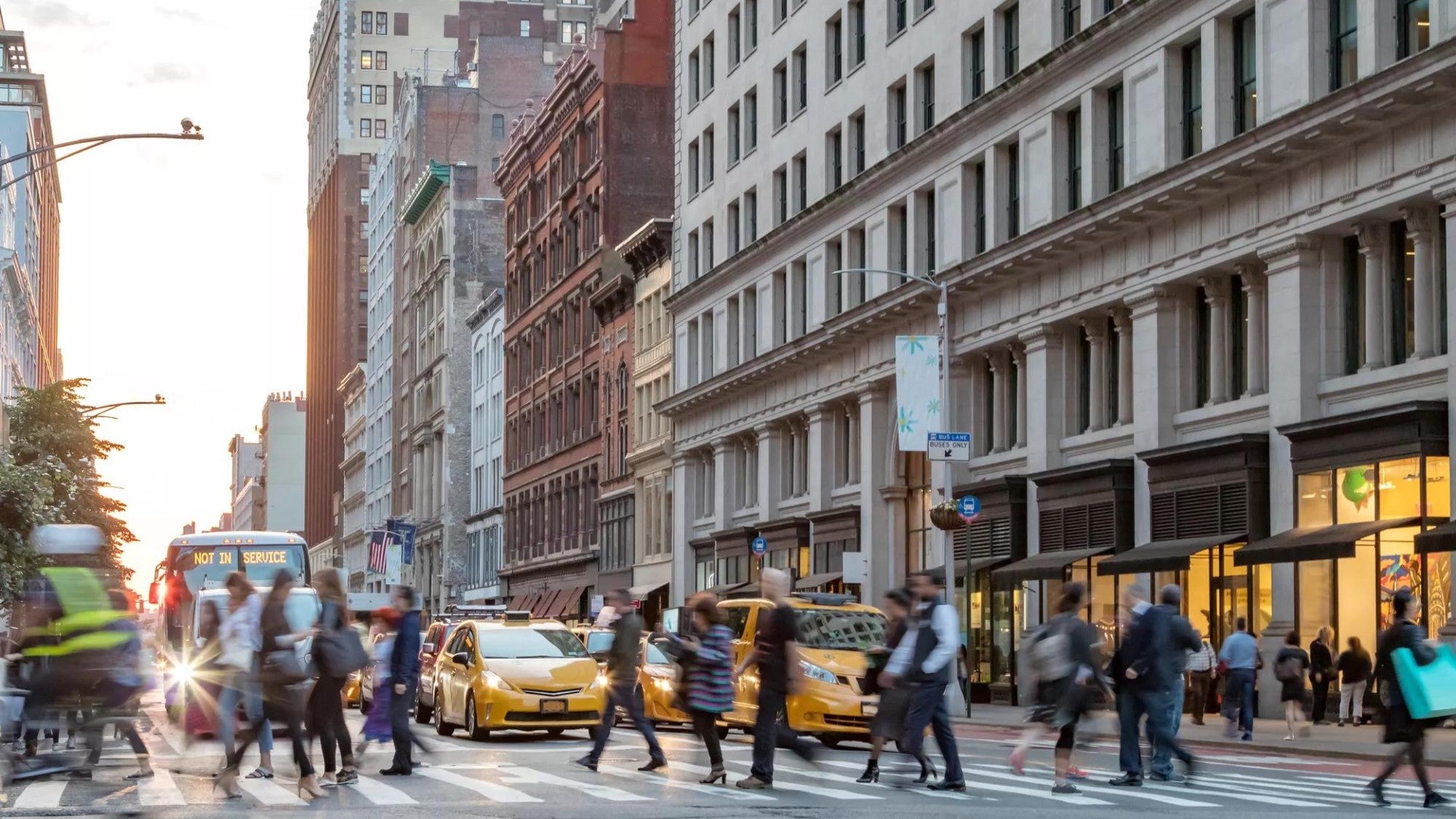 Fast paced street scene with people walking across a busy intersection on Broadway in Manhattan New York City