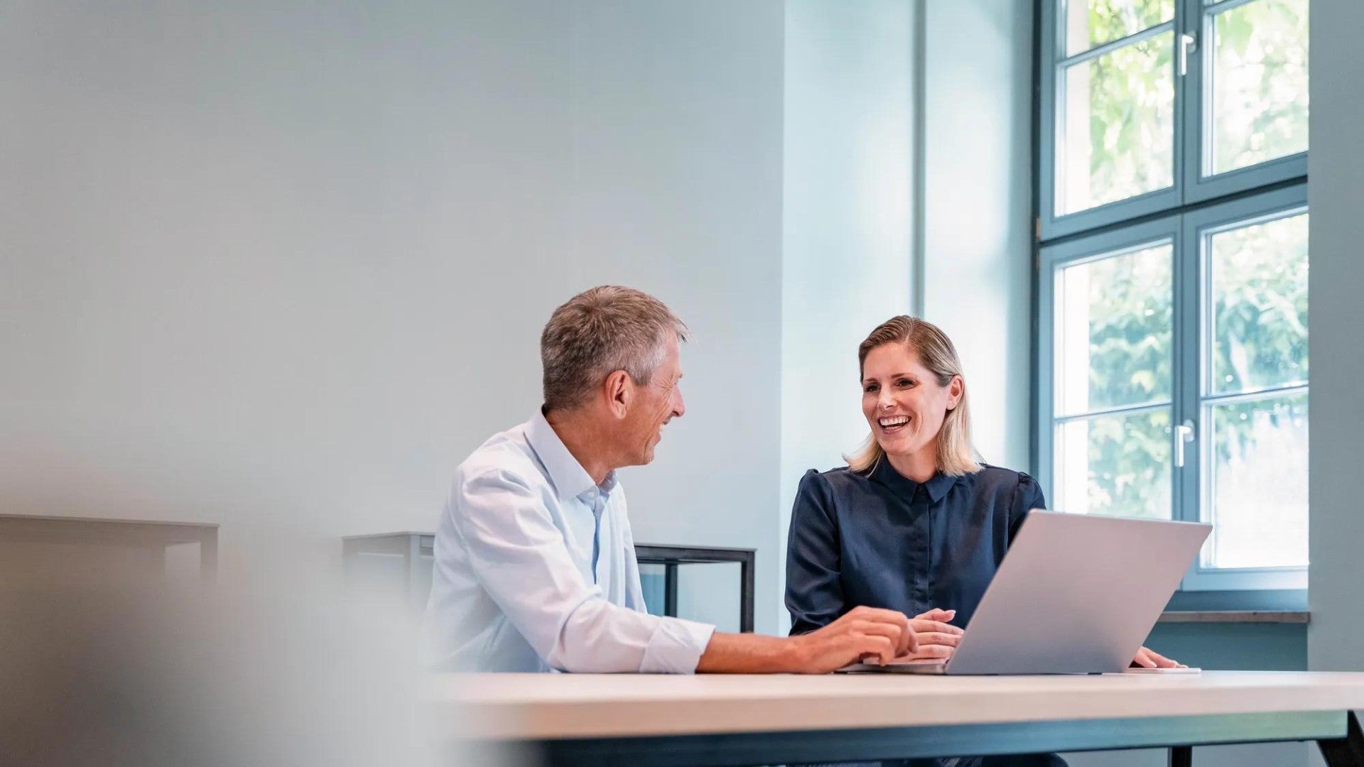 Happy businesswoman discussing with businessman at desk