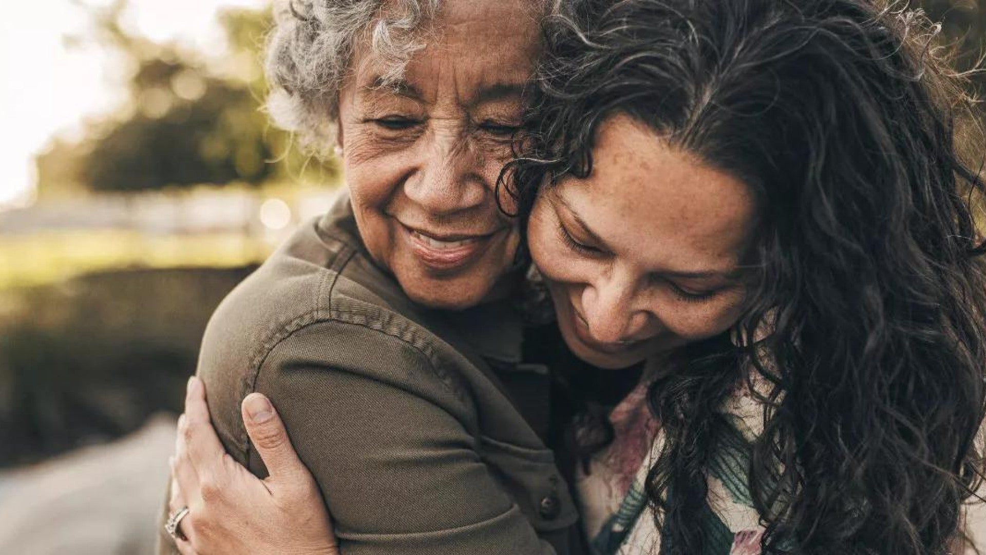 An older adult and her daughter smile and hug.