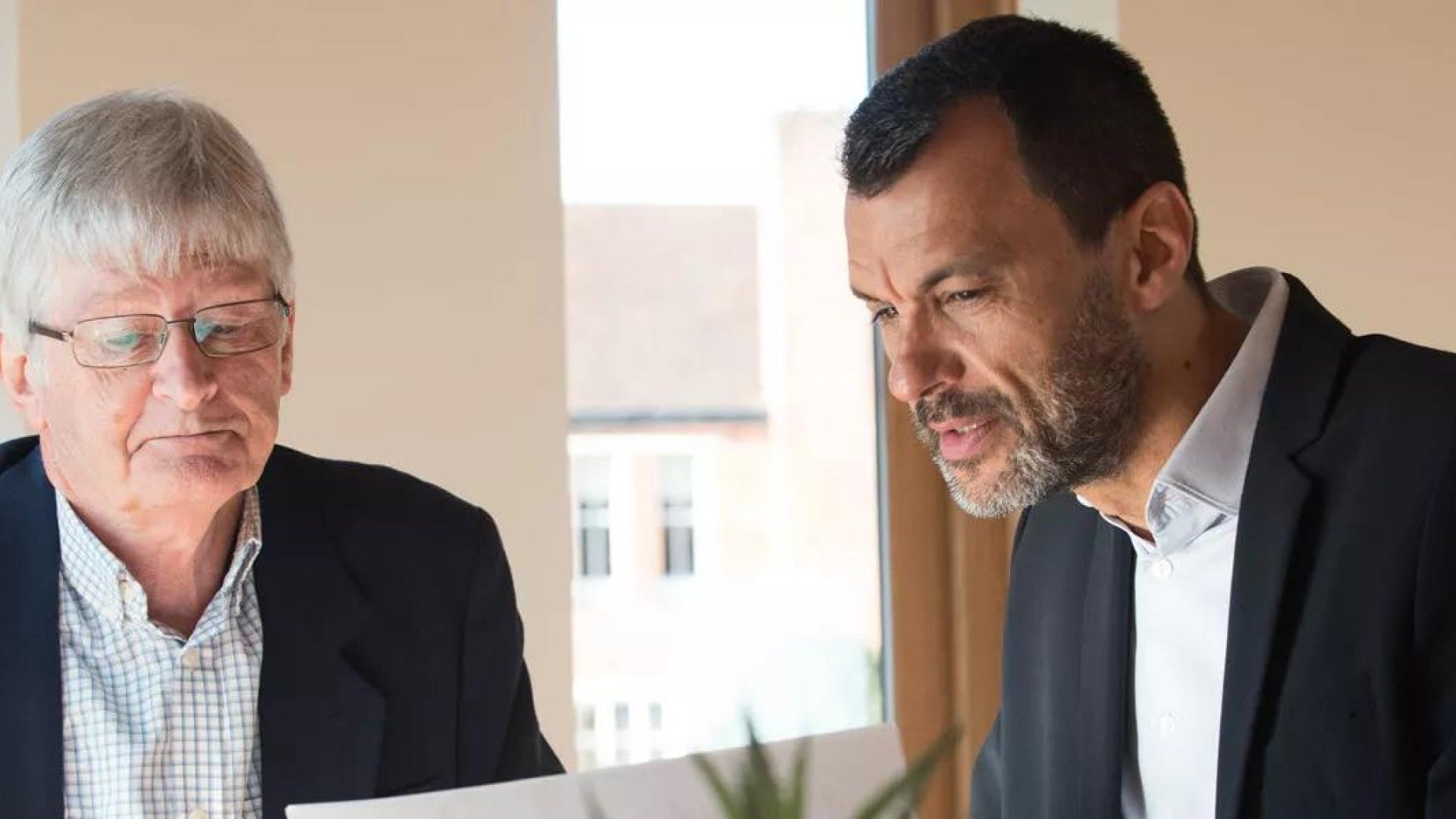 Two business people looking at a report on a sheet of paper.