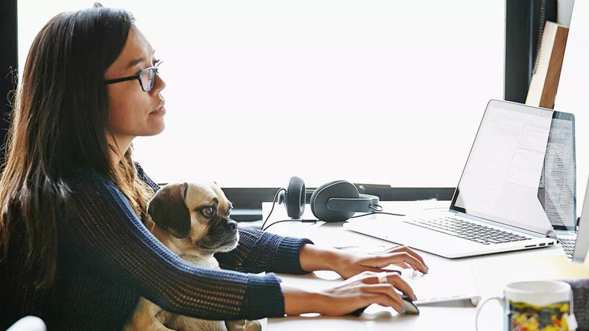 A woman prioritizing the benefits she offers to her employees. A puppy sits in her lap.