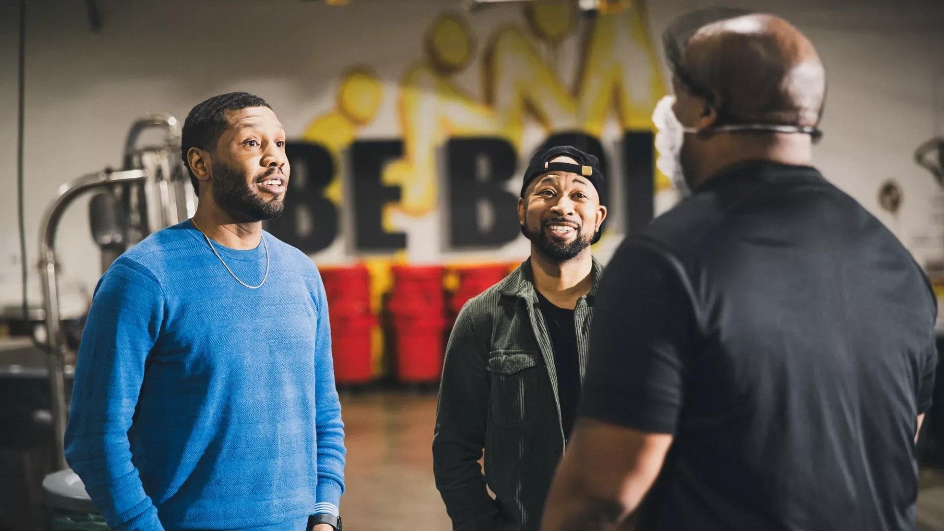 Business owners smiling while talking to their employee working in a roastery.