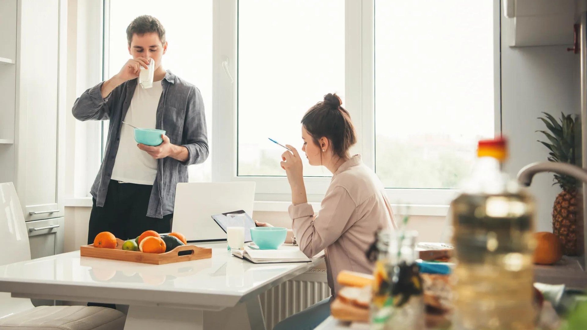 Young male and female couple eating breakfast at home while going over finances. Young male and female couple eating breakfast at home while going over finances.