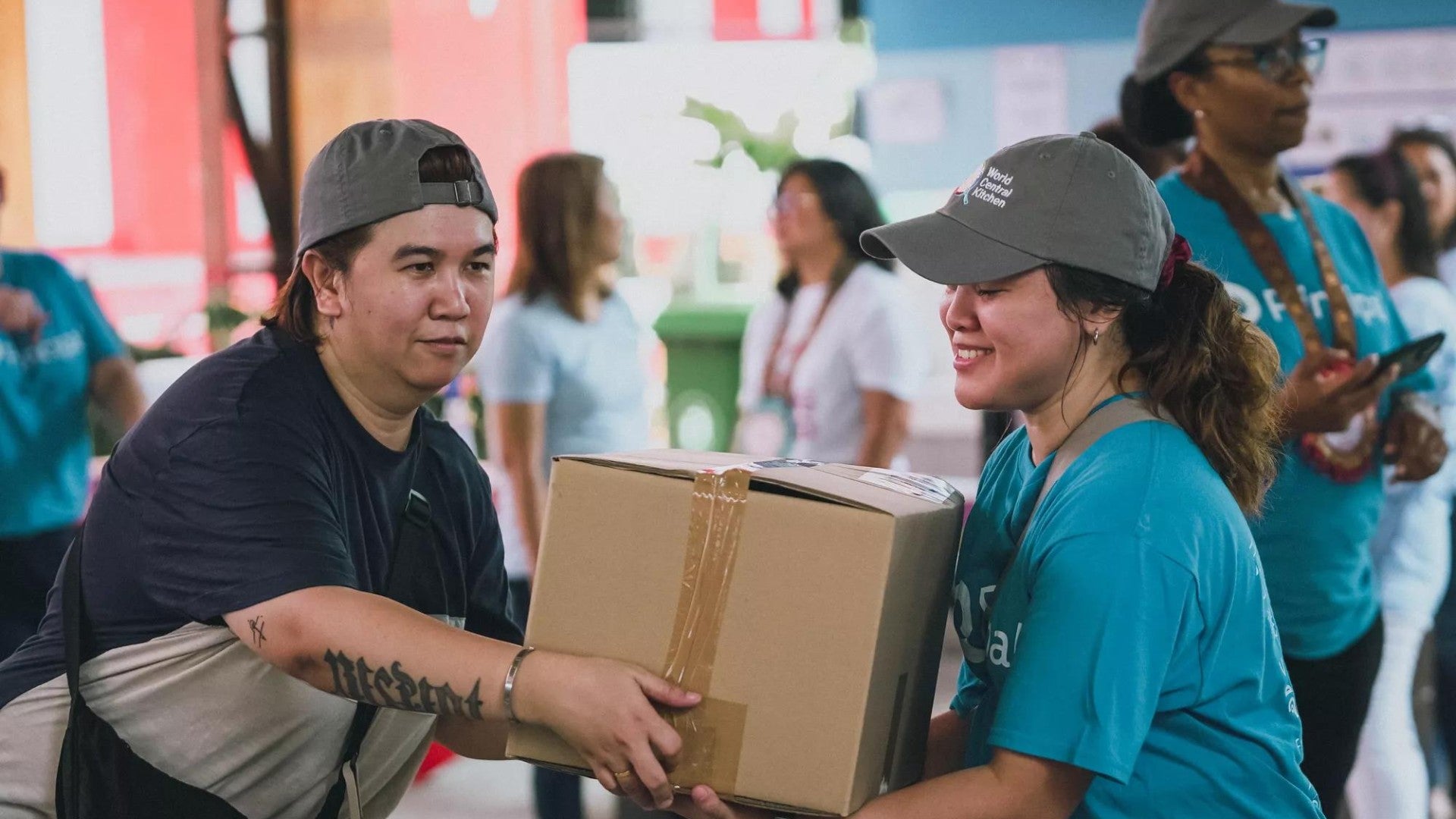 Principal employees work together to carry a box at the World Central Kitchen volunteer event.