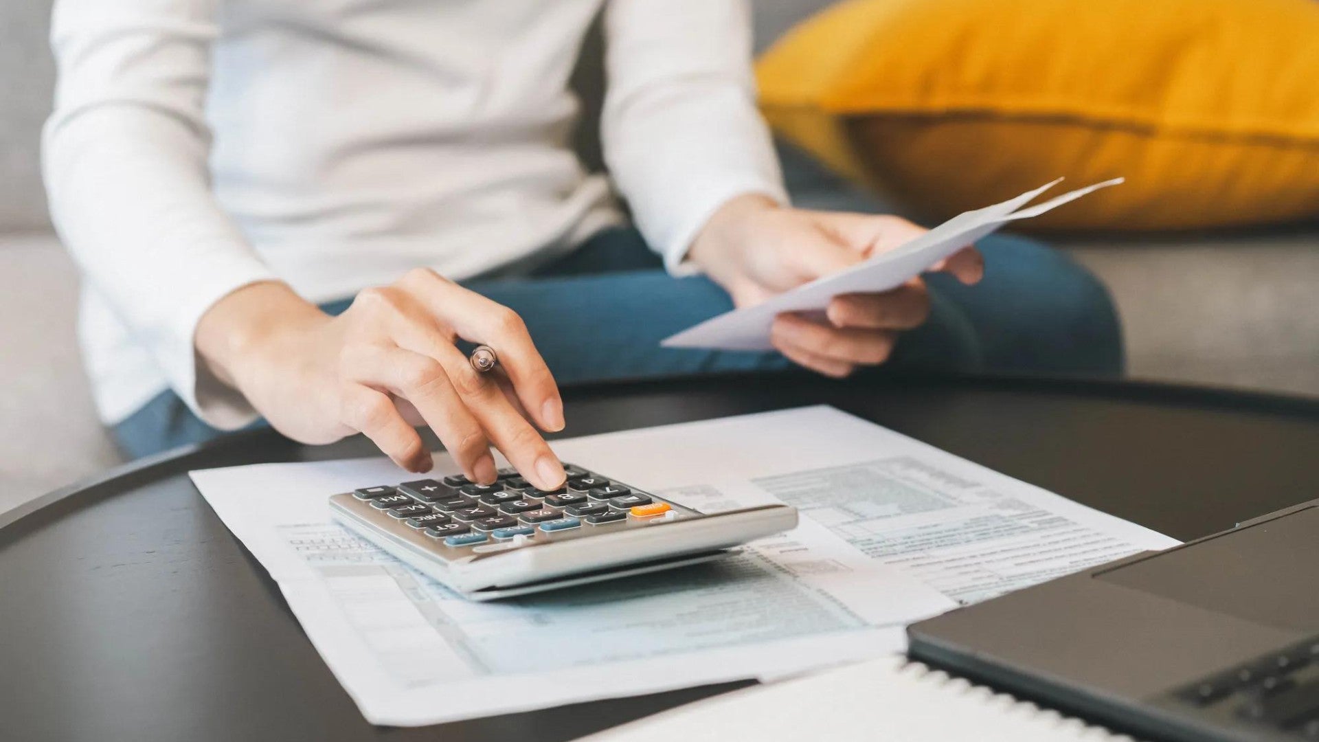 Una mujer utilizando una calculadora para calcular sus impuestos.