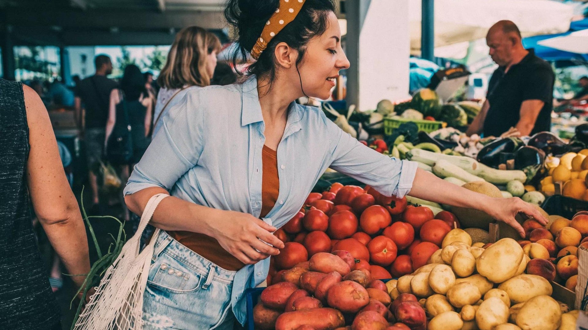 A young woman buys vegetables and fruits at the market . 