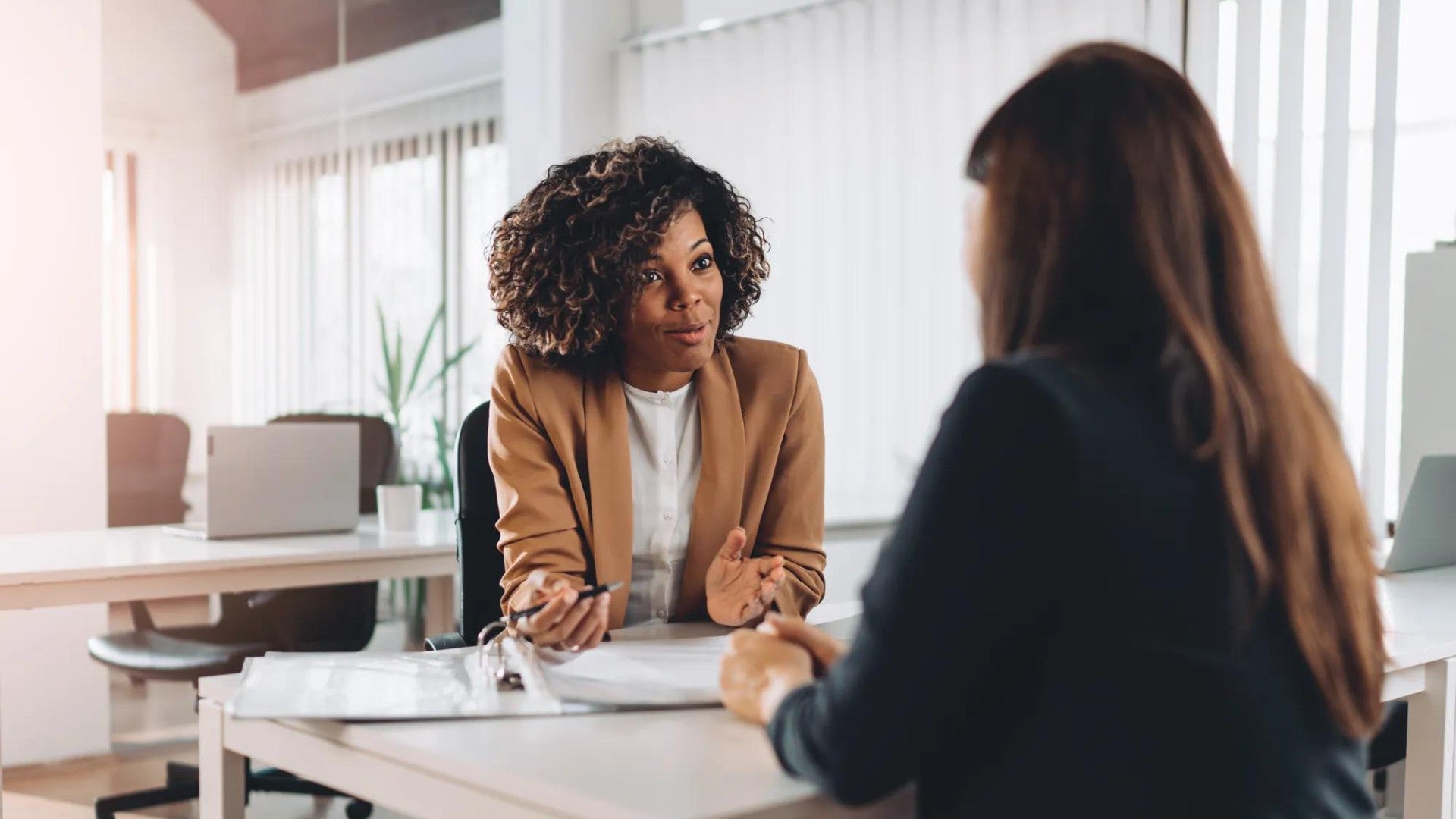 Two women sitting across from one another at a desk.