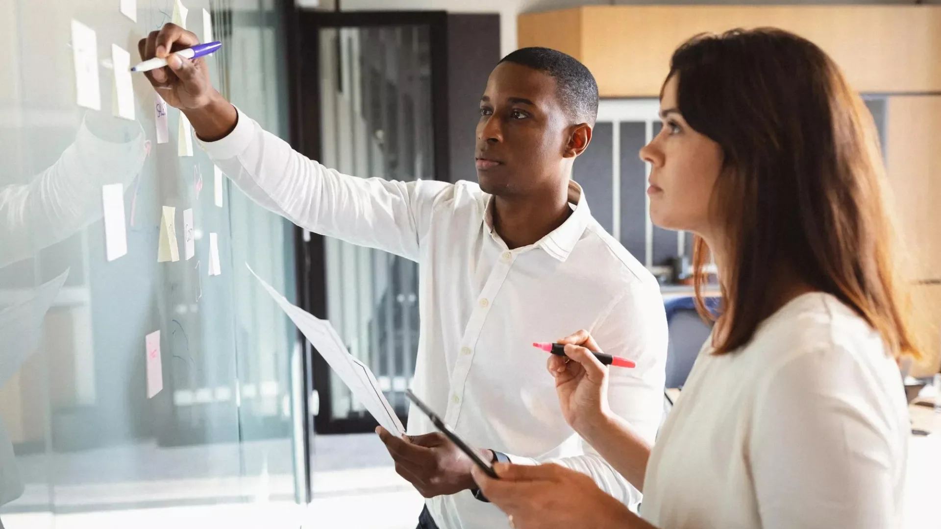 Two co-workers at a whiteboard.