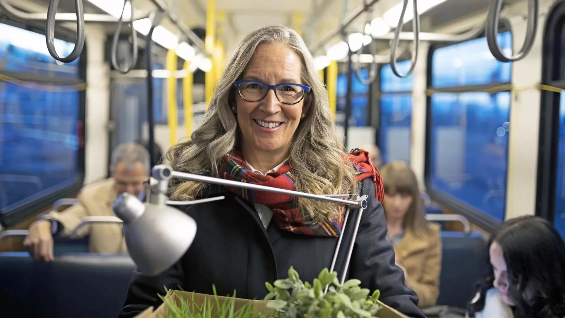 Mature woman who is retiring and on a bus carrying a box of belongings.