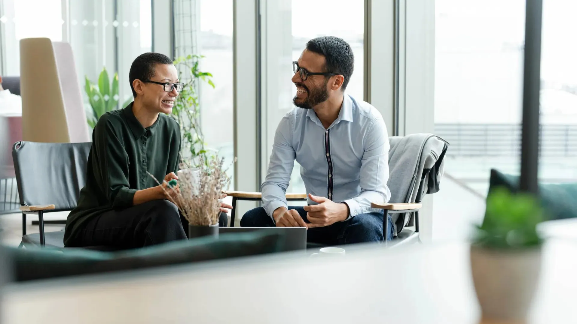 Two smiling employees meeting in an office environment.