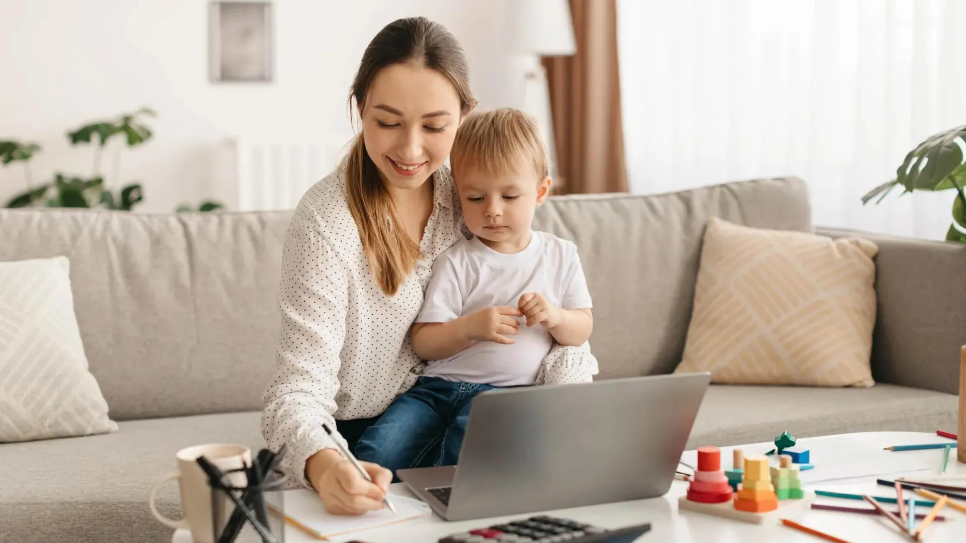 Woman working on budget and goals with toddler sitting on her lap.