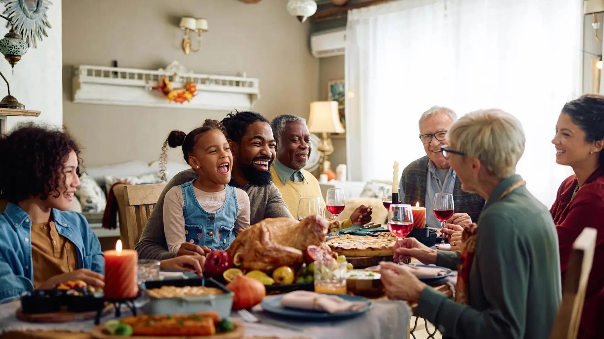 A happy family representing at least three generations sits around the dinner table to share a meal.