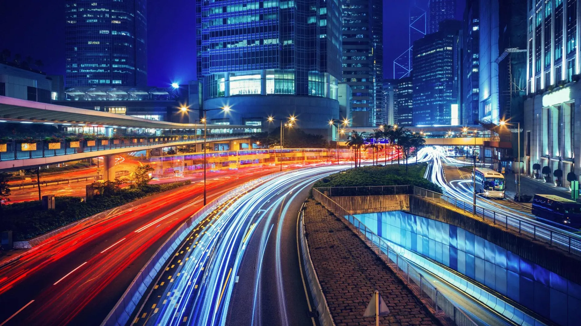 Long exposure nighttime photograph of a curved highway in a modern city.