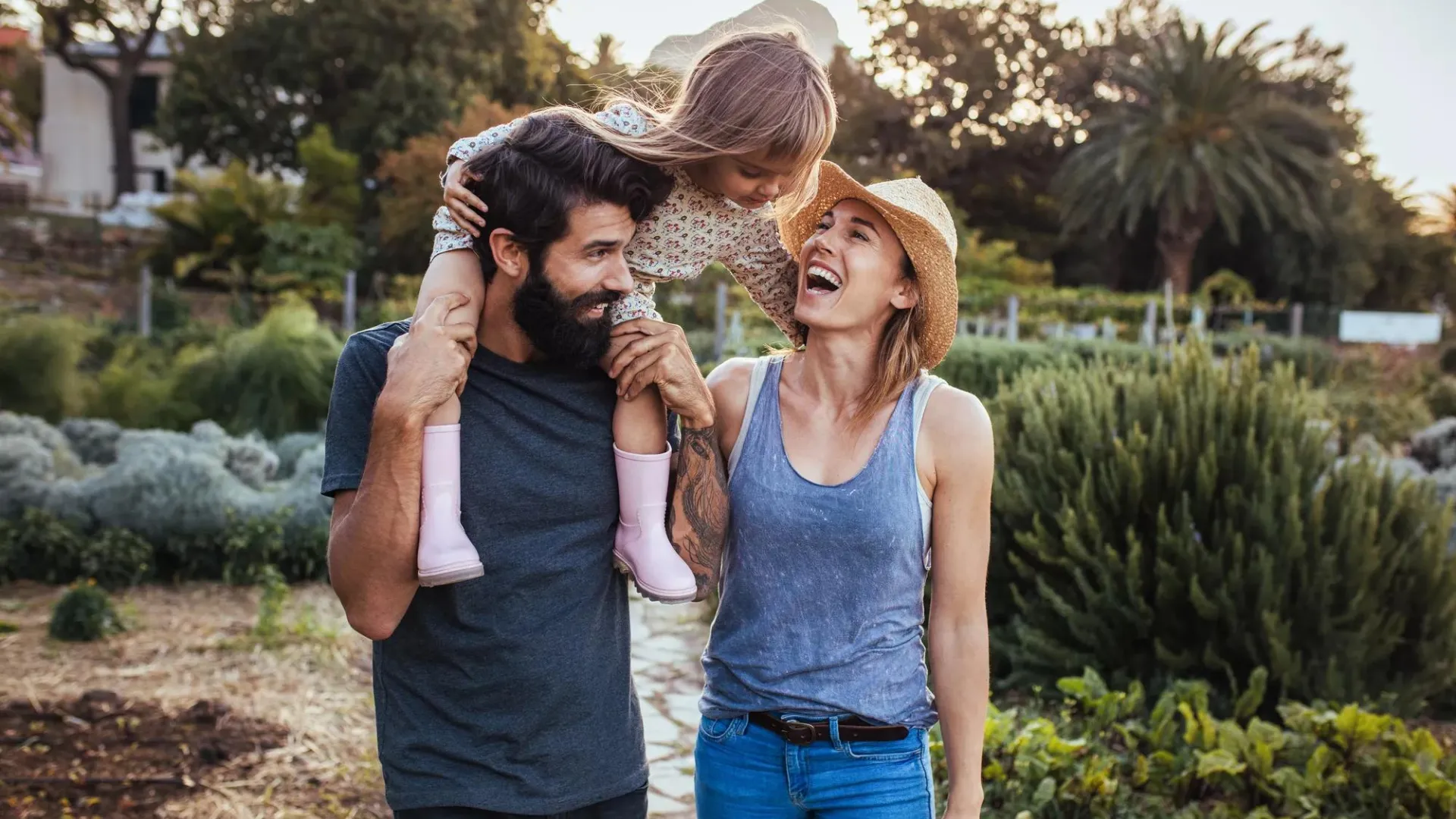 Millennial man and woman walking in nature with child on man's shoulders.