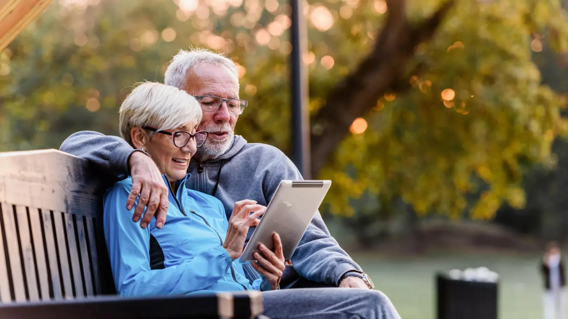 Older couple sitting on park bench discussing retirement benefits through Social Security.
