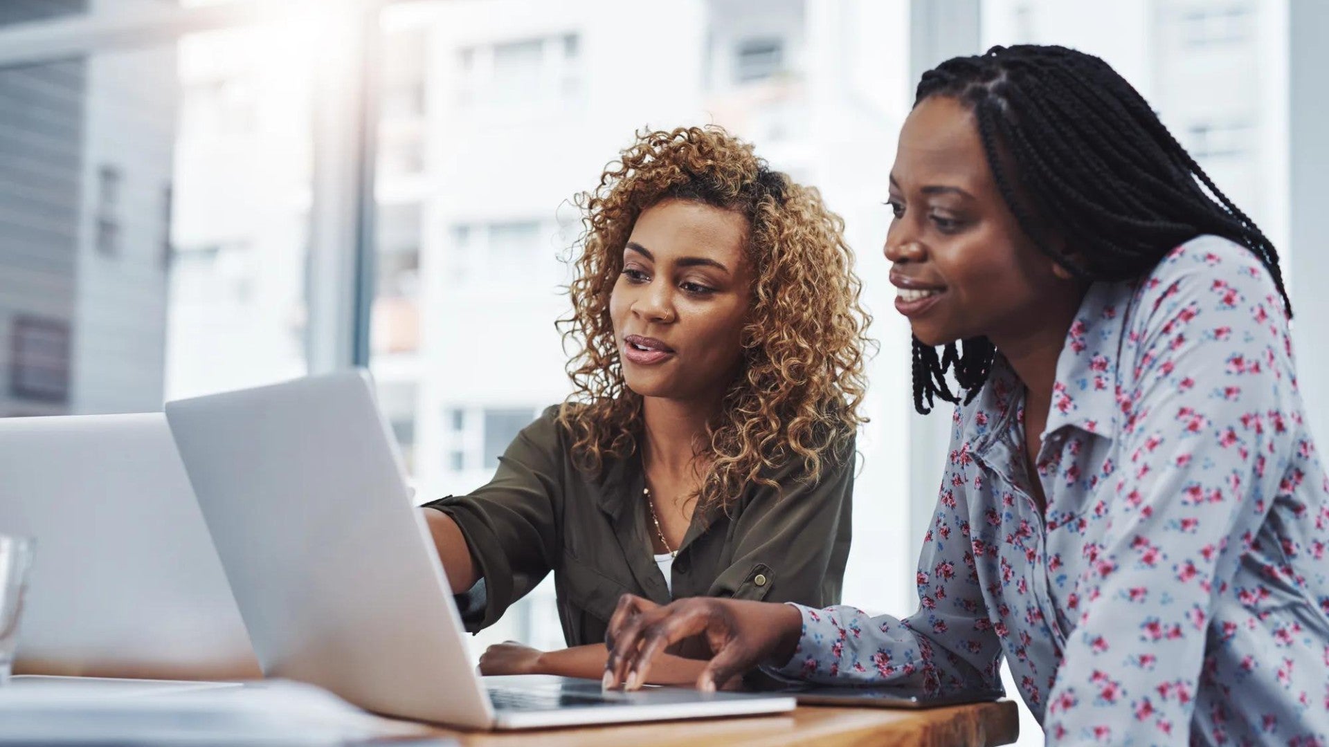 Two Black women reviewing financial information on computers.