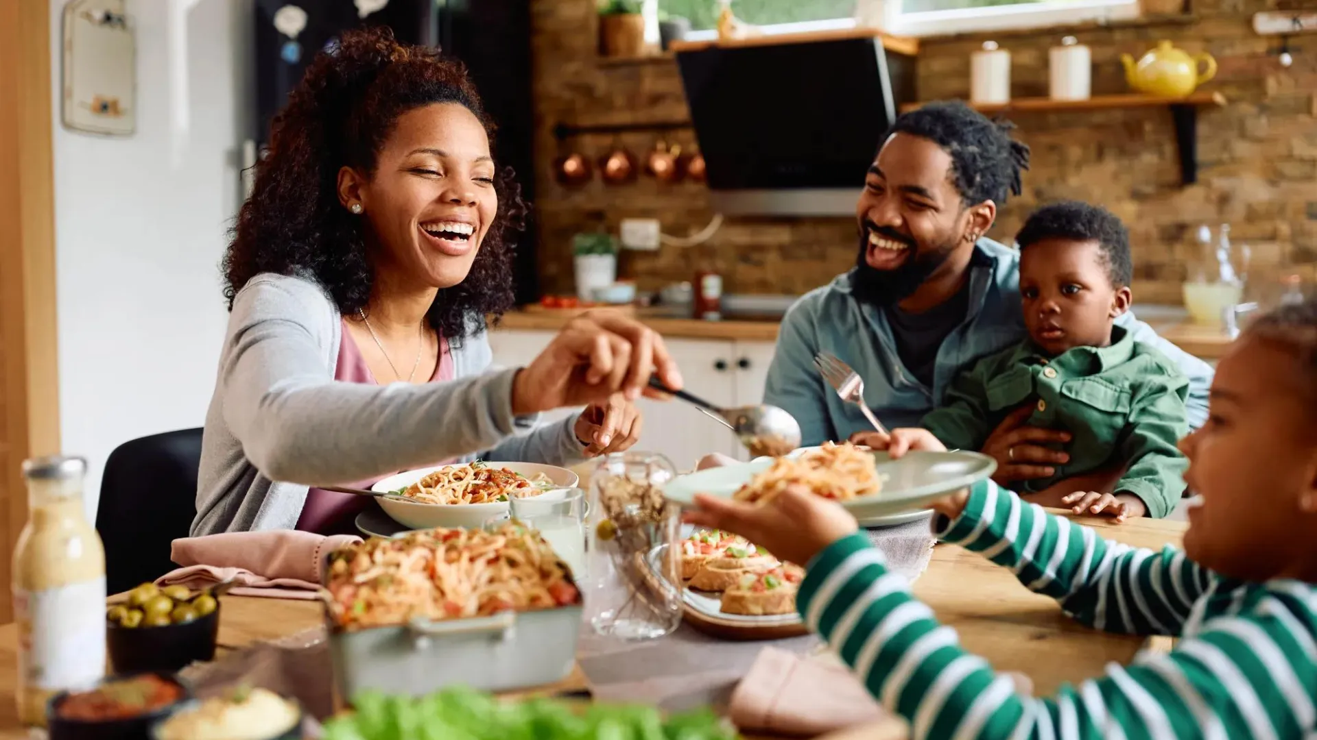Familiy with parents and two children gathered around a table eating a meal.