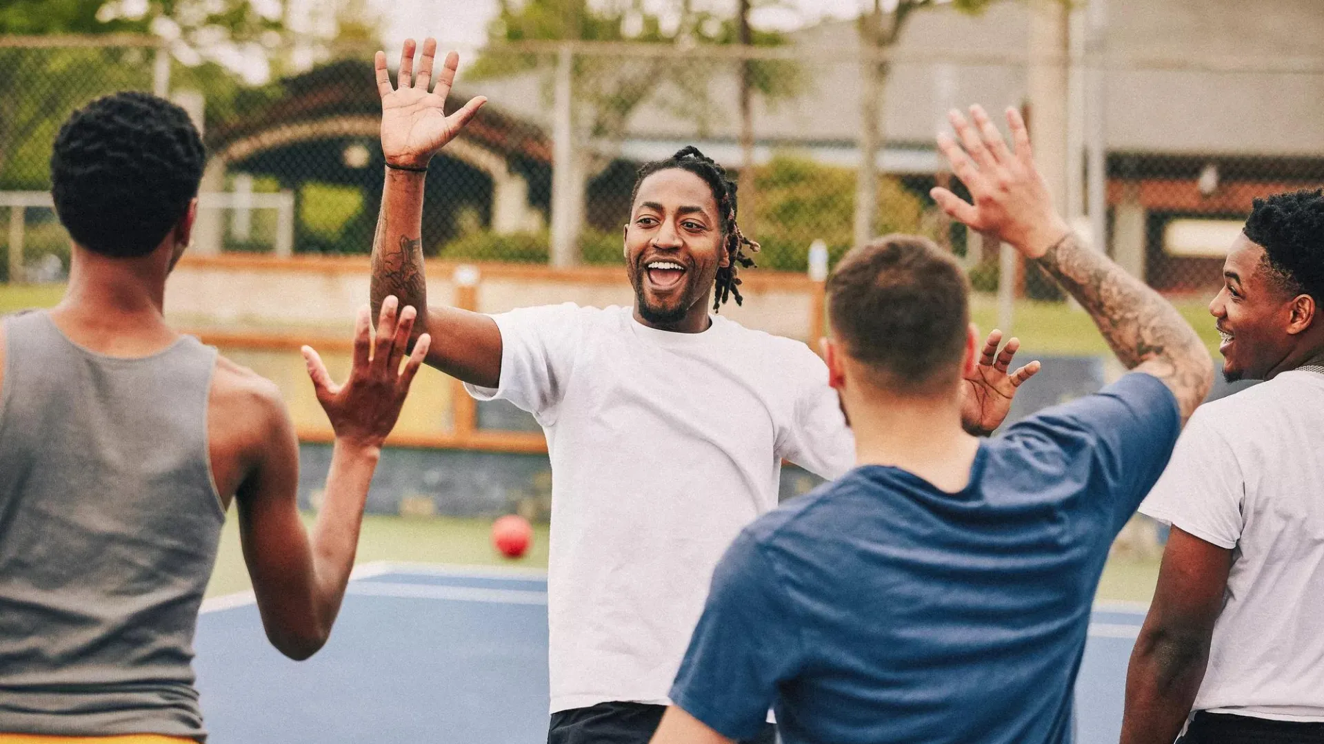 A group of athletic men high-fiving about their strong game performance—a comparative image of defined benefit (DB) plan sponsor