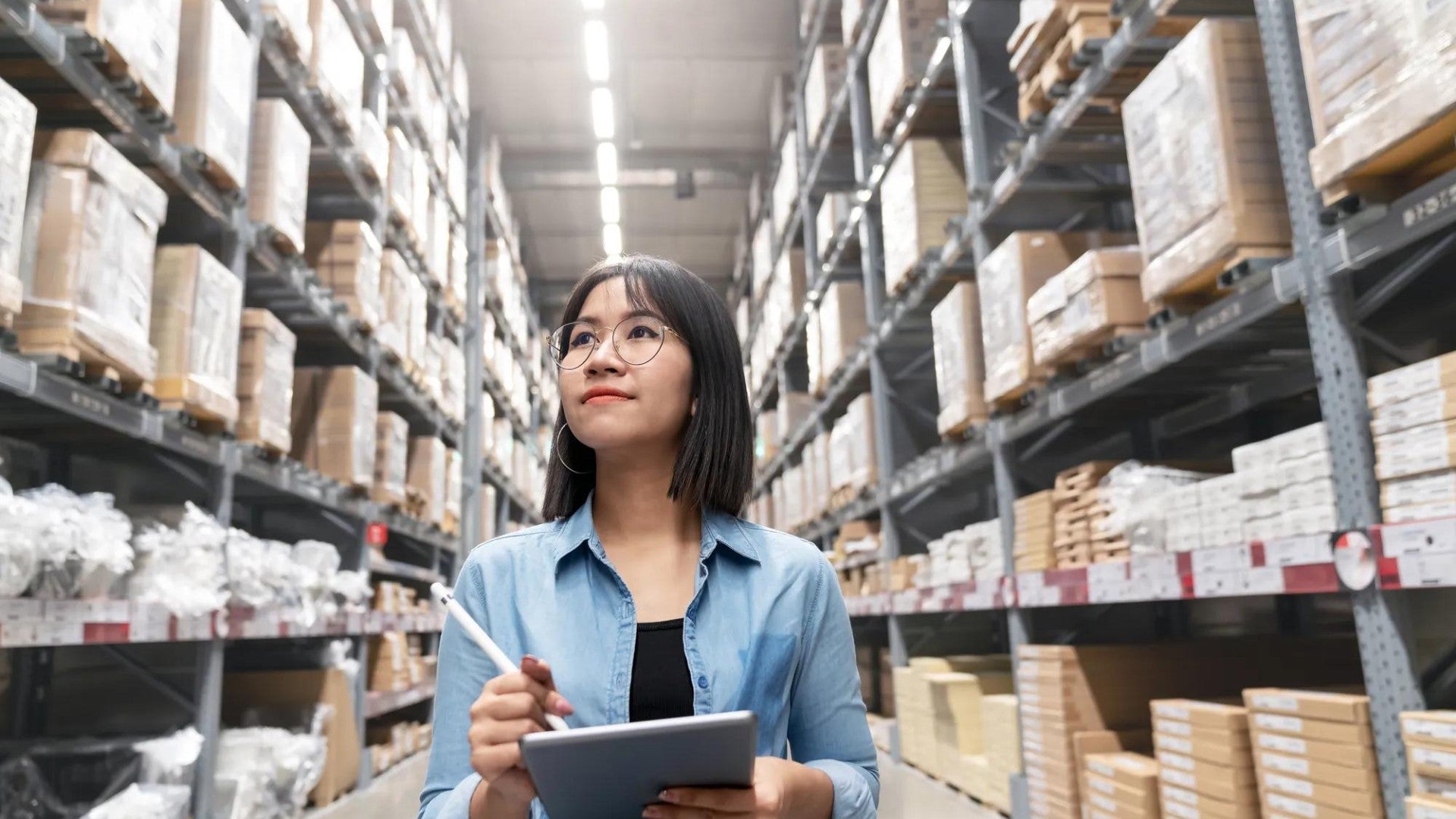 A woman taking inventory in a large aisle of supplies and products.