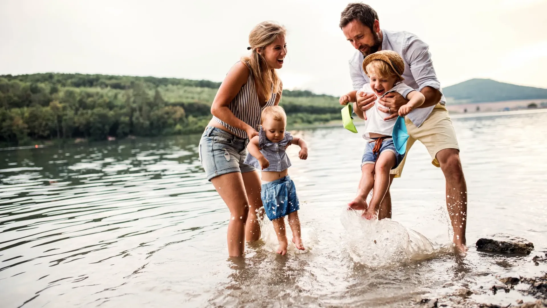 Dos padres y dos niños jugando en el agua.