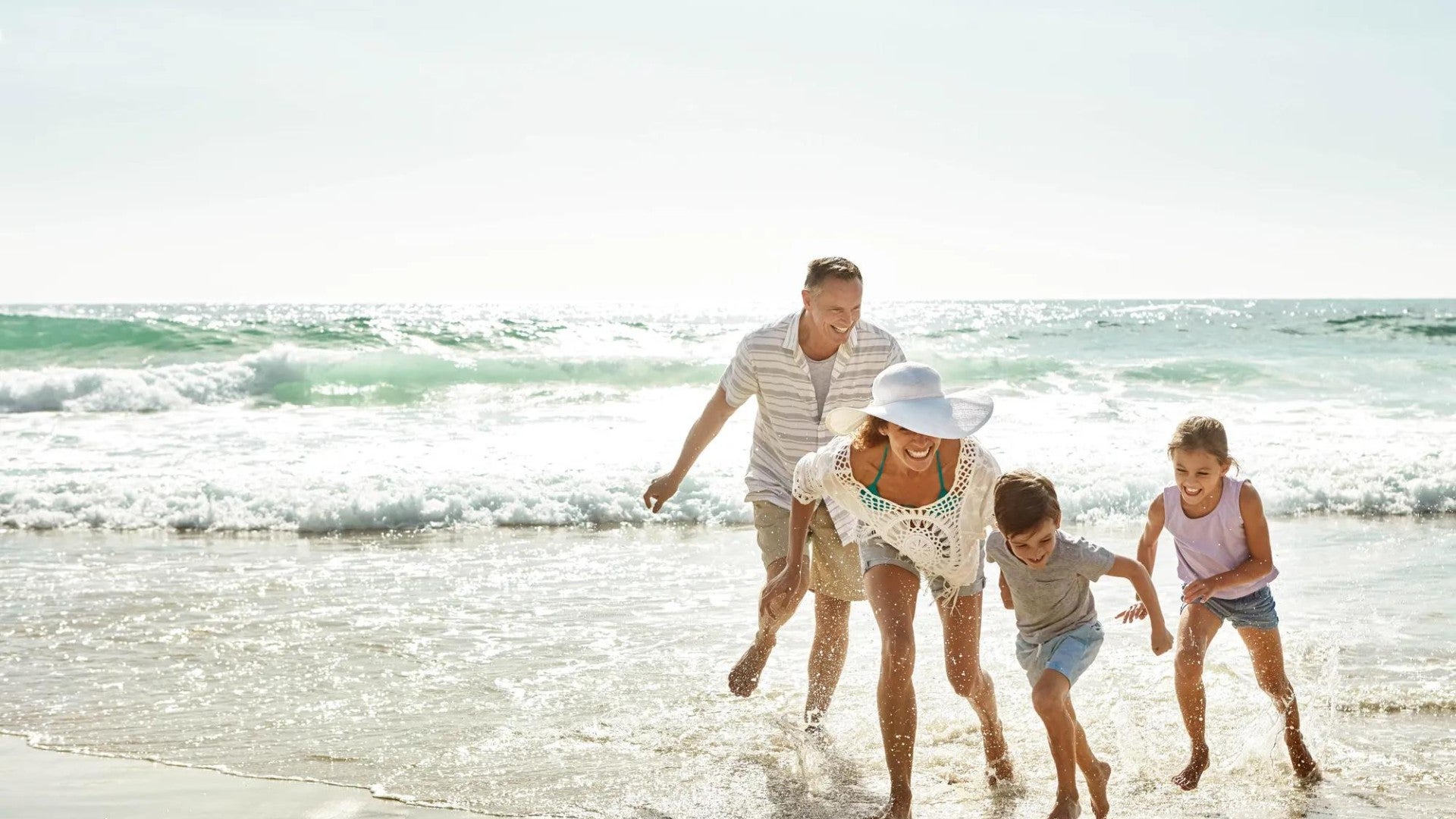 Man, woman, and two children playing in the ocean.