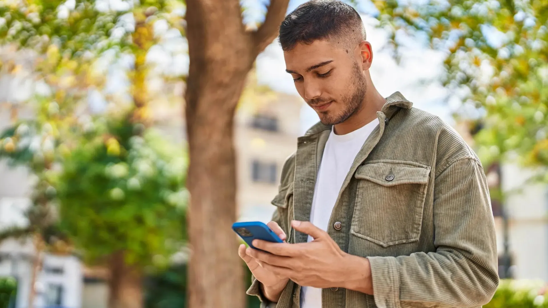 Man in an outdoor setting looking at his cell phone.