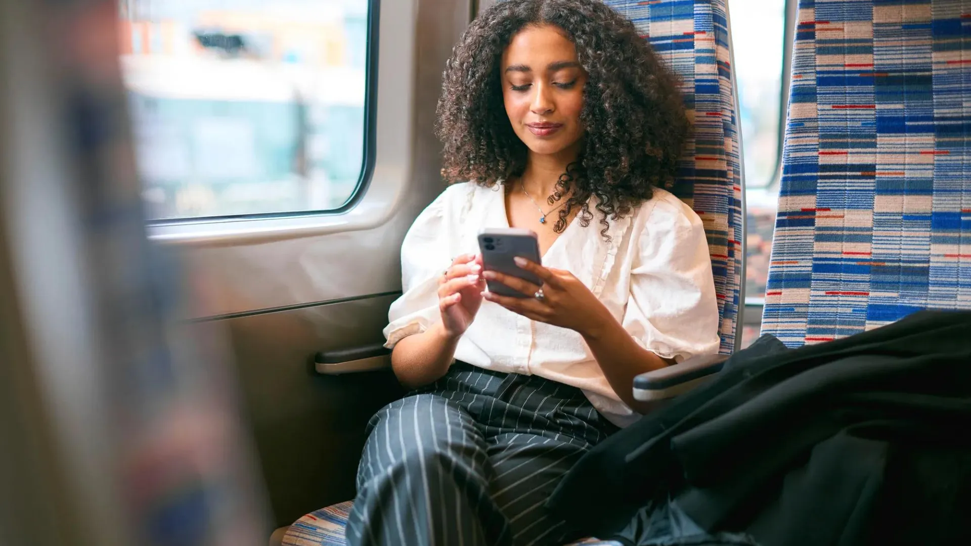 A woman looking at her phone in a seat while travelling.