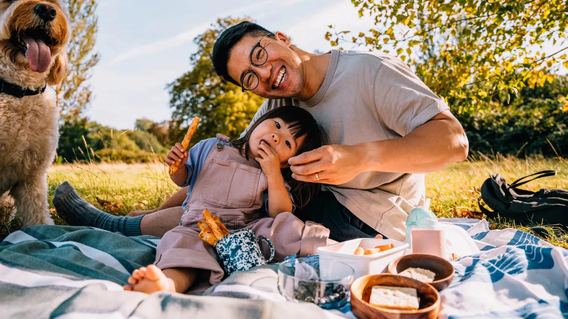 Father and daughter outside sitting on blanket having a picnic