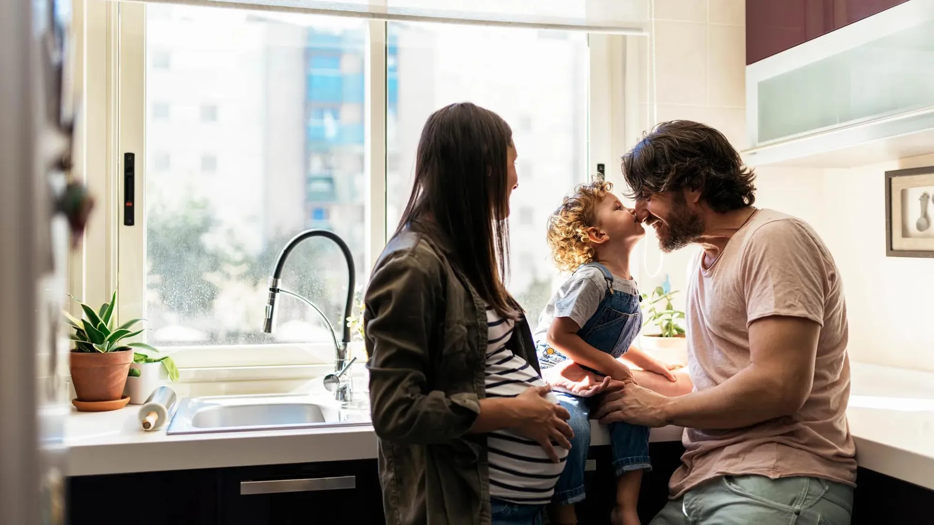 A young family sharing a tender moment in their kitchen.