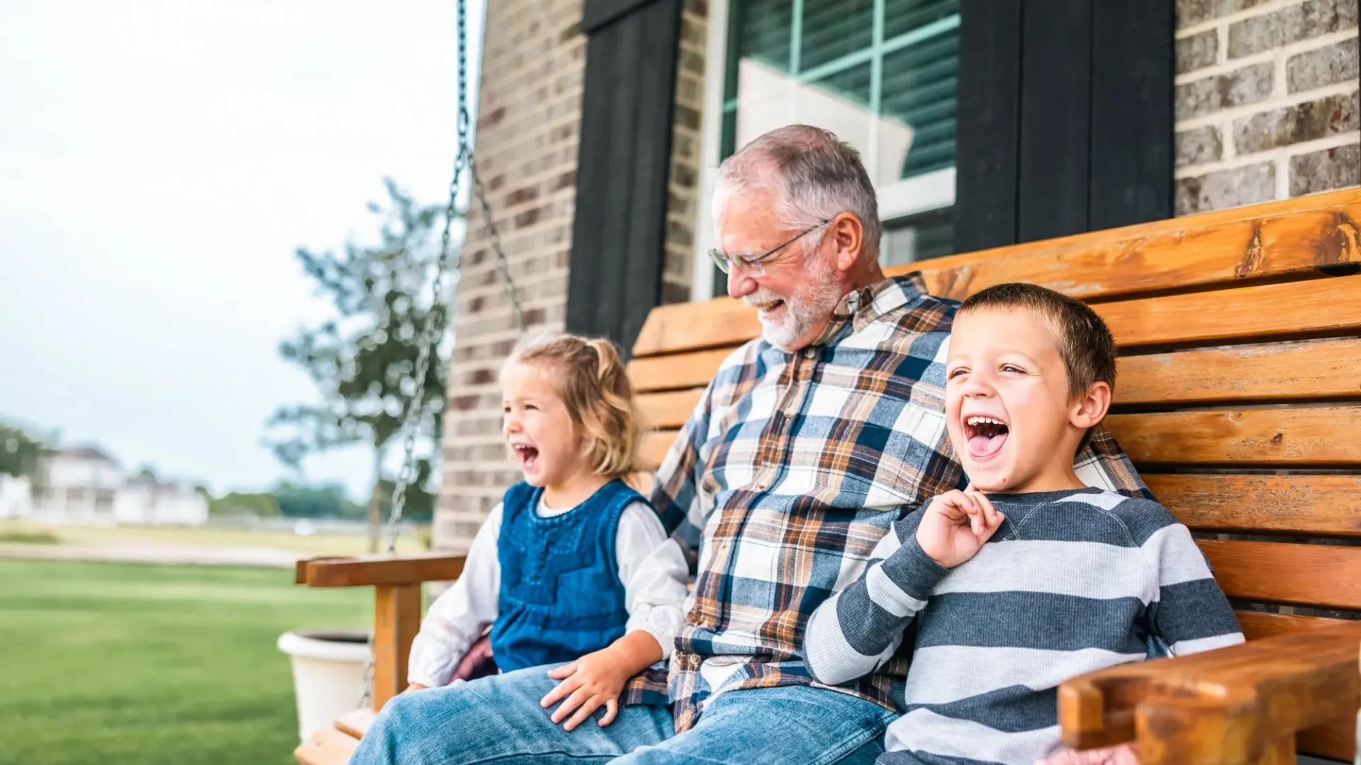 Grandfather sitting on porch swing with two grandchildren