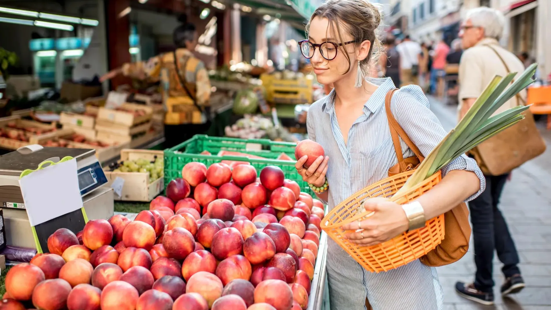 Young woman choosing fresh fruit at a farmers market