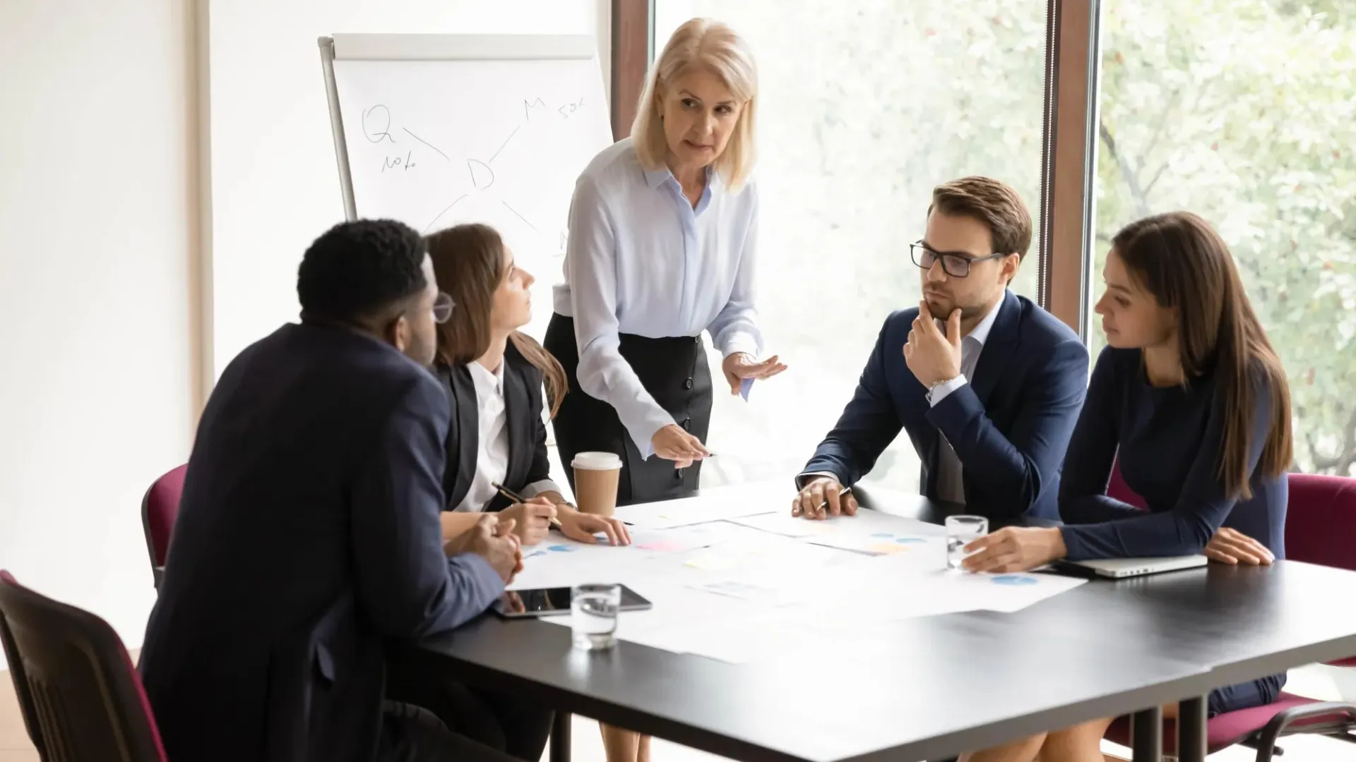 Concentrated female leader heading a diverse group of business people cooperating together