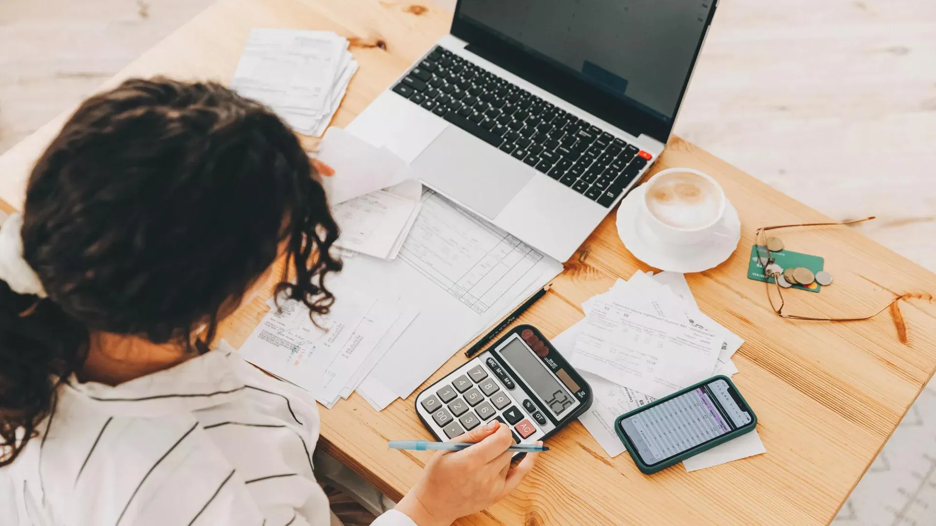 Woman working on taxes and retirement planning using calculator and notebook.