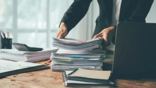 Pila de papeles financieros en un escritorio.