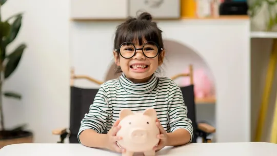 A young girl smiling with her piggy bank.
