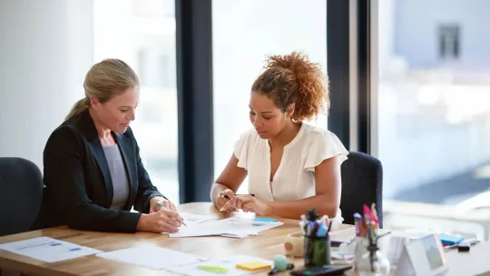 Two women sitting at a desk reviewing financial information