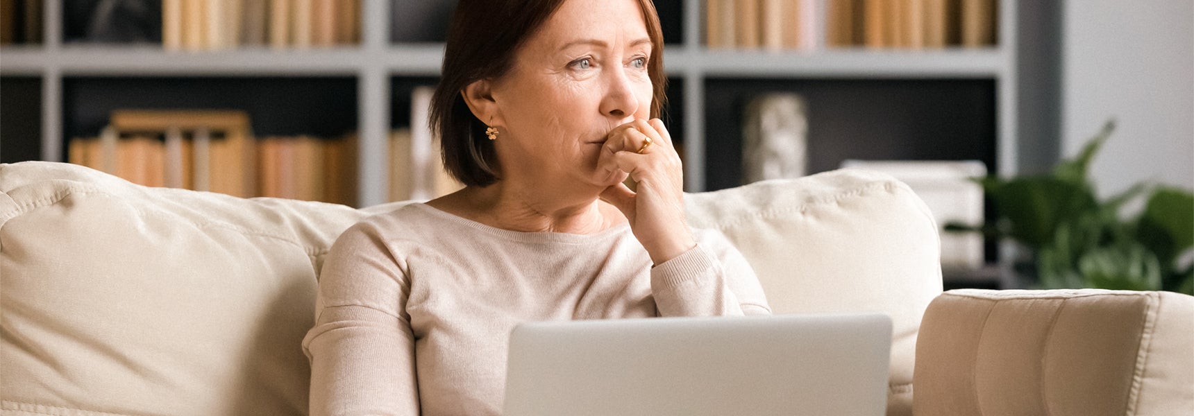 Photo of an older woman sitting on the couch and thinking about how market volatility may affect her retirement.