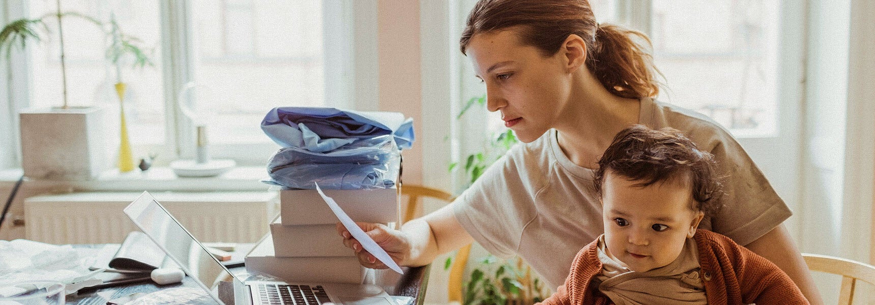 Photo of a mother holding her baby while looking at options for emergency cash.