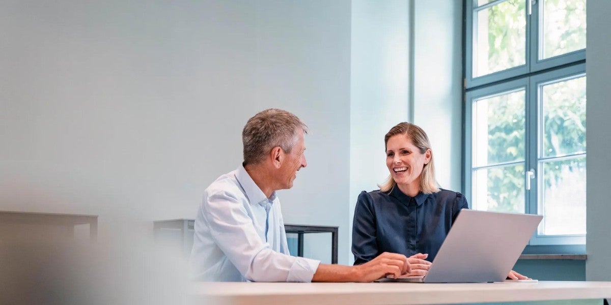 Happy businesswoman discussing with businessman at desk