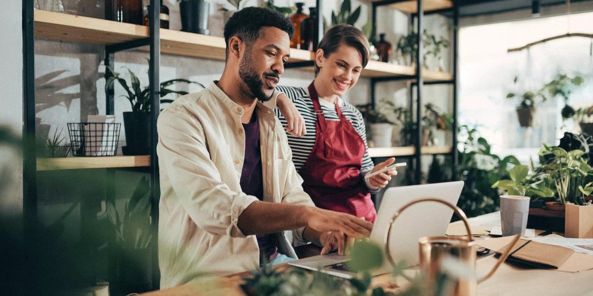 Two people looking at a laptop working together in a plant shop.