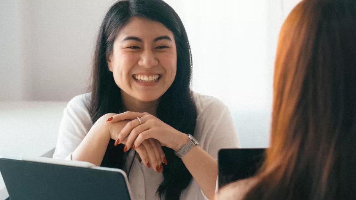 Two people working on laptops and one is smiling