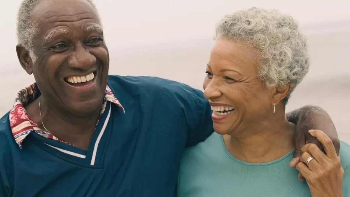 Photo of an older man and woman walking, embracing, and smiling