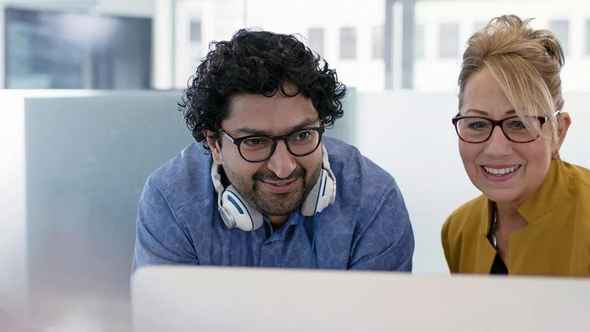 Two smiling coworkers looking at the same screen.