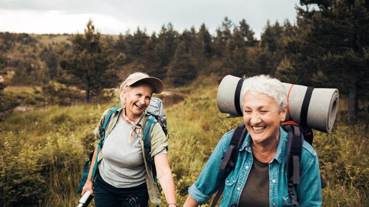 Close up of two senior females hiking together.