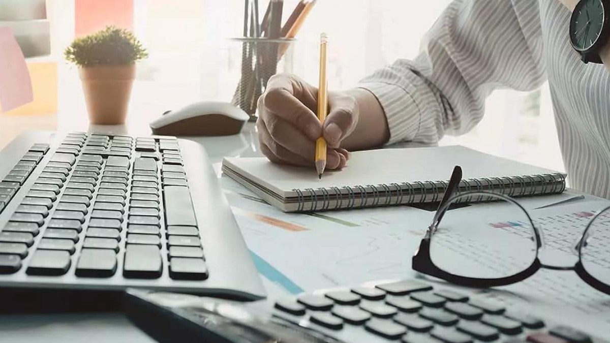 Person sitting at desk writing on notepad