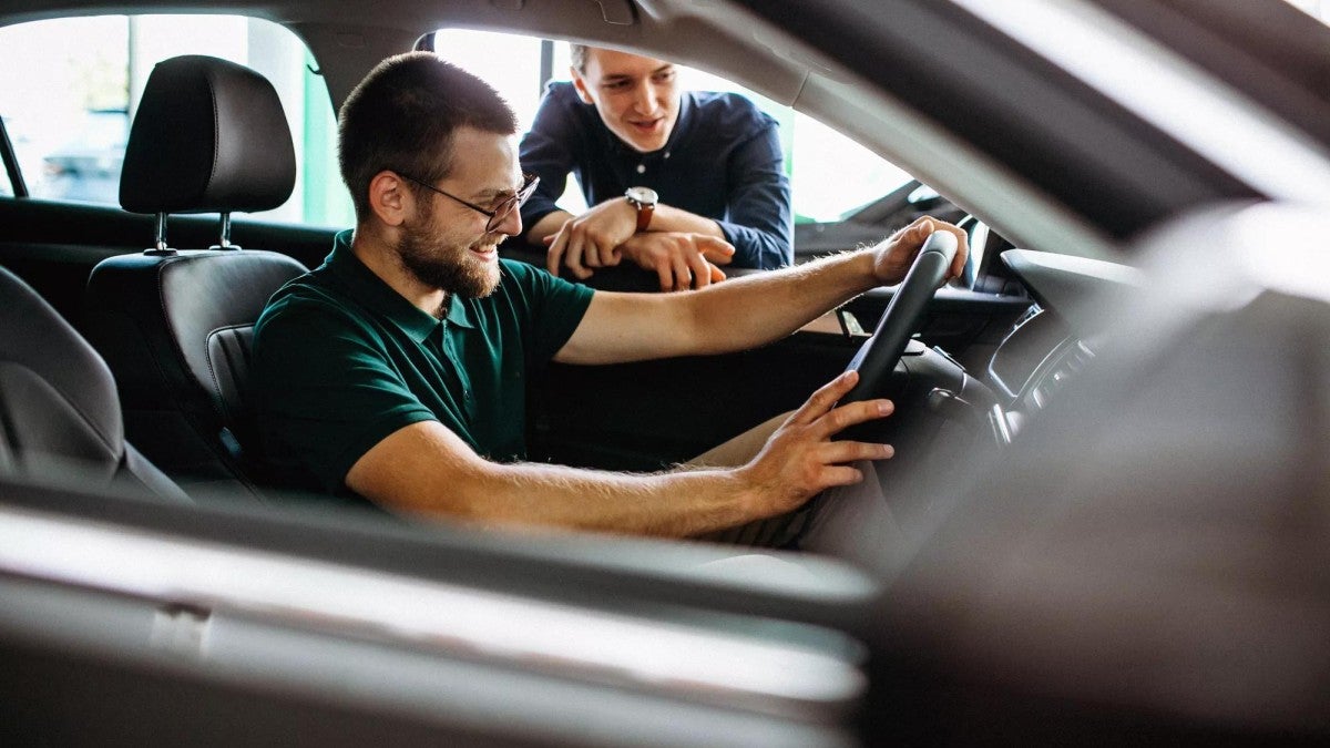 Young man testing new car at a showroom