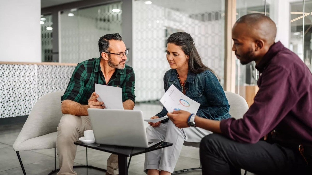 A financial professional sitting with a husband and wife, reviewing retirement documents.